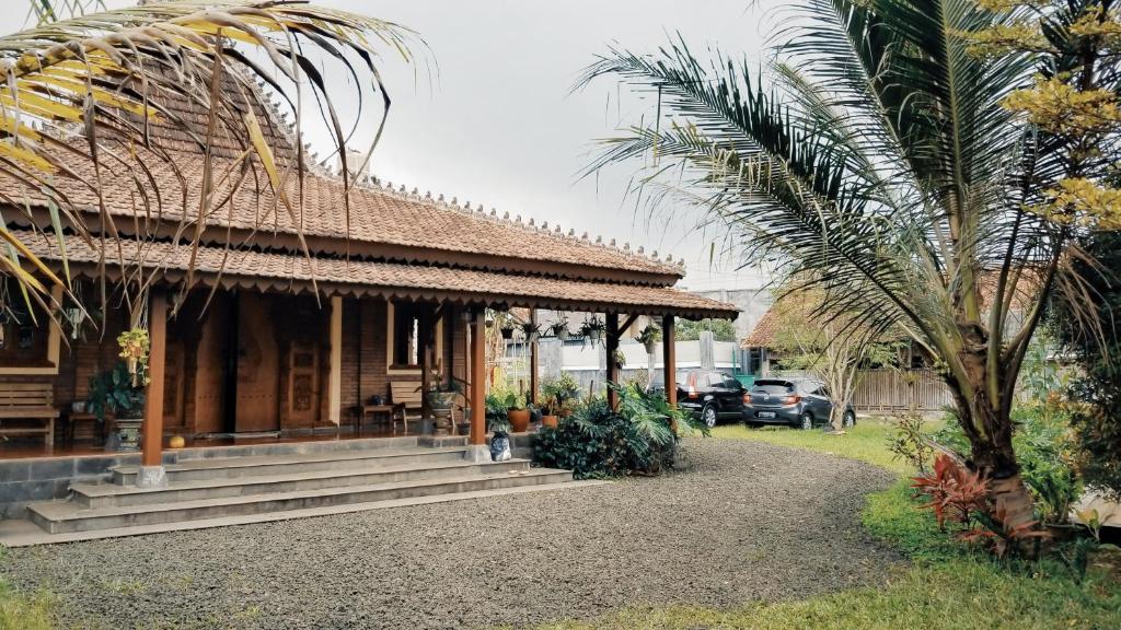 a house with a palm tree in front of it at Villa Joglo Cimande in Bogor