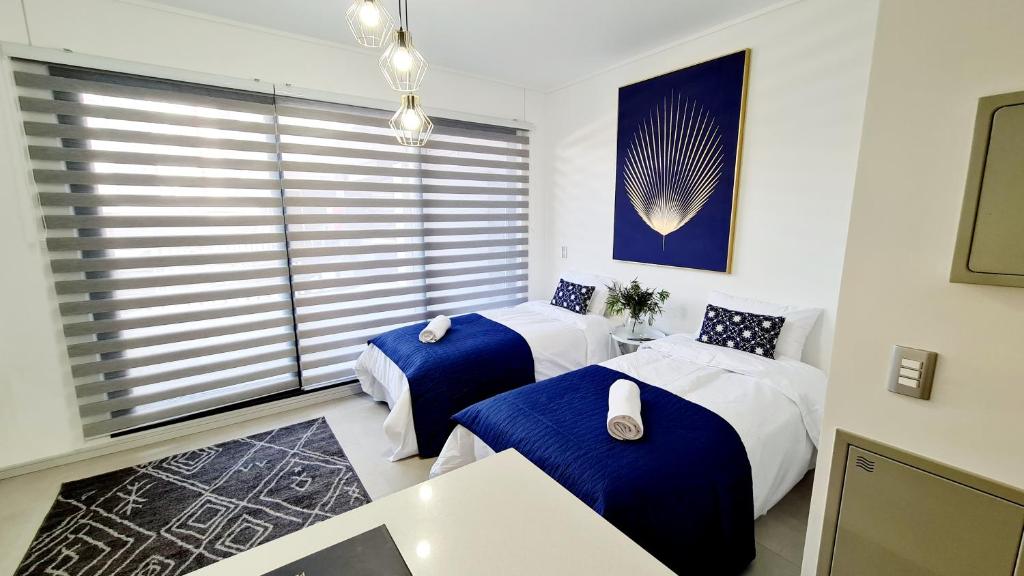 a bedroom with two beds and a table and a window at Curitiba VIP Studio 21 in Temuco