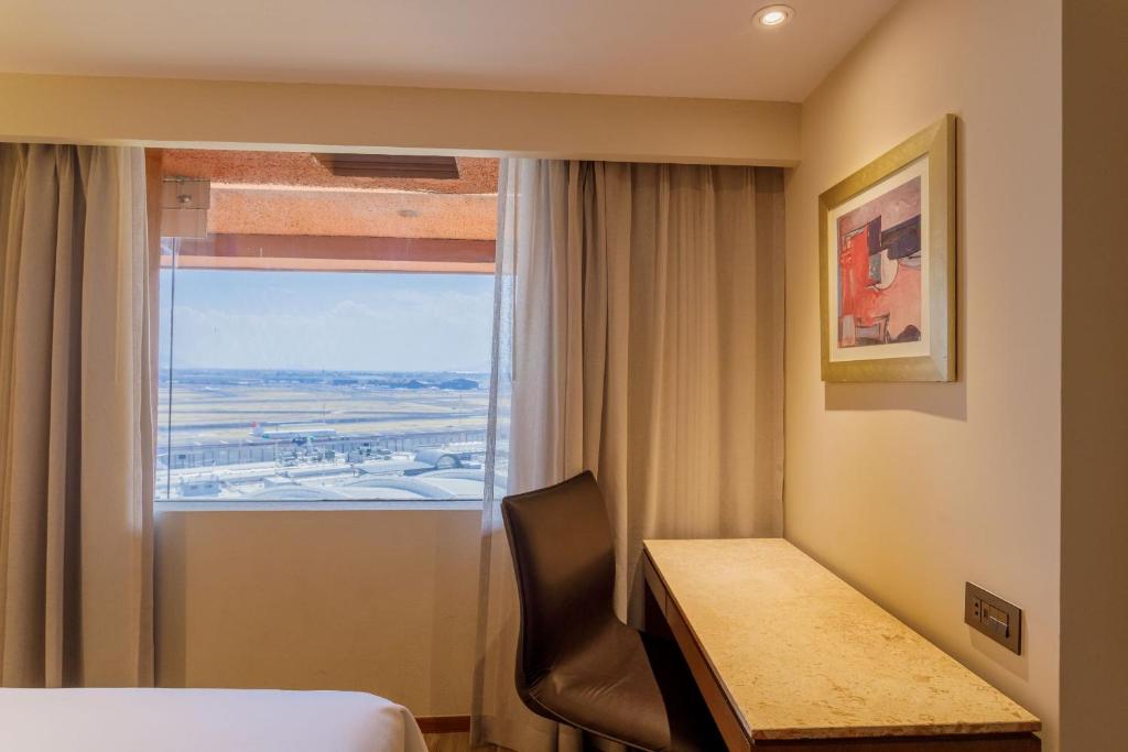 a room with a desk and a bed and a window at Camino Real Aeropuerto in Mexico City