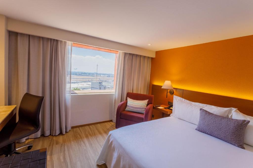 a hotel room with a bed and a desk and a window at Camino Real Aeropuerto in Mexico City