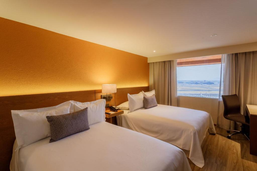 a hotel room with two beds and a window at Camino Real Aeropuerto in Mexico City