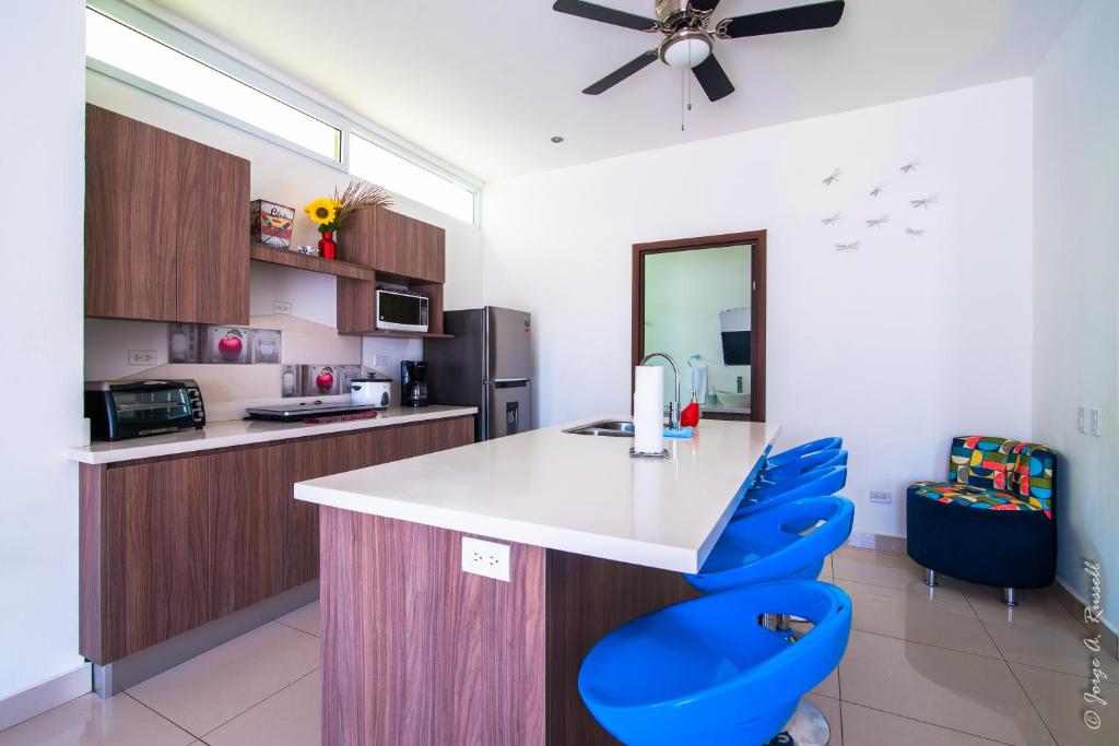 a kitchen with a white counter and blue chairs at Jaco Modern & Beach Apartment - Lapa Living A1 in Jacó