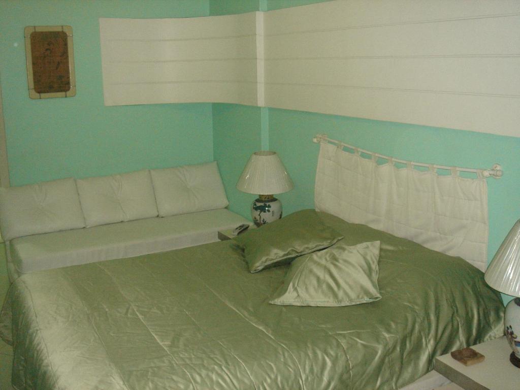 1 dormitorio con cama verde y banco en Studio Copacabana 1003, en Río de Janeiro