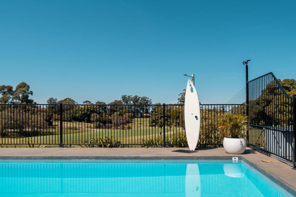 a surfboard leaning against a fence next to a pool at The Select Inn Ryde in Sydney