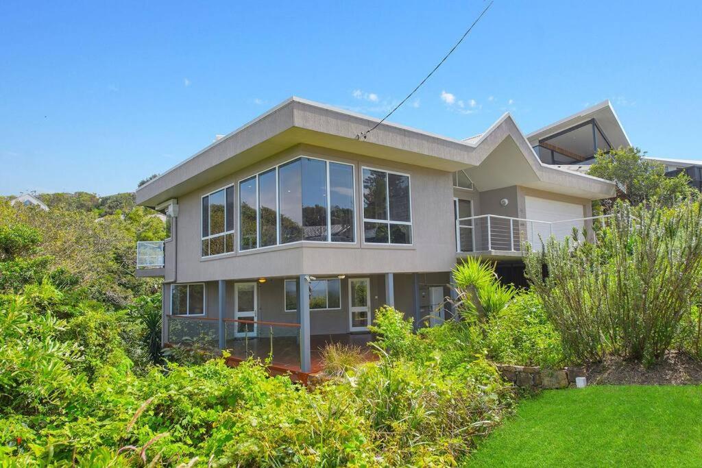 une grande maison avec des fenêtres en verre sur une colline dans l'établissement Watonga Waves, à Port Macquarie