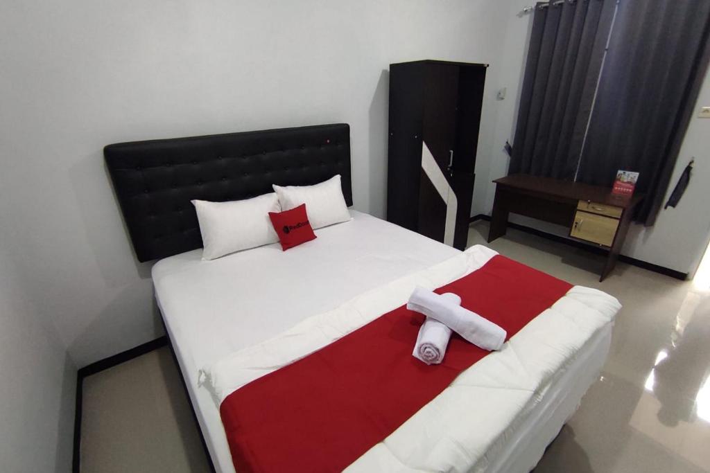a bedroom with a bed with a red and white blanket at RedDoorz Syariah near Alun Alun Purwokerto 2 in Purwokerto