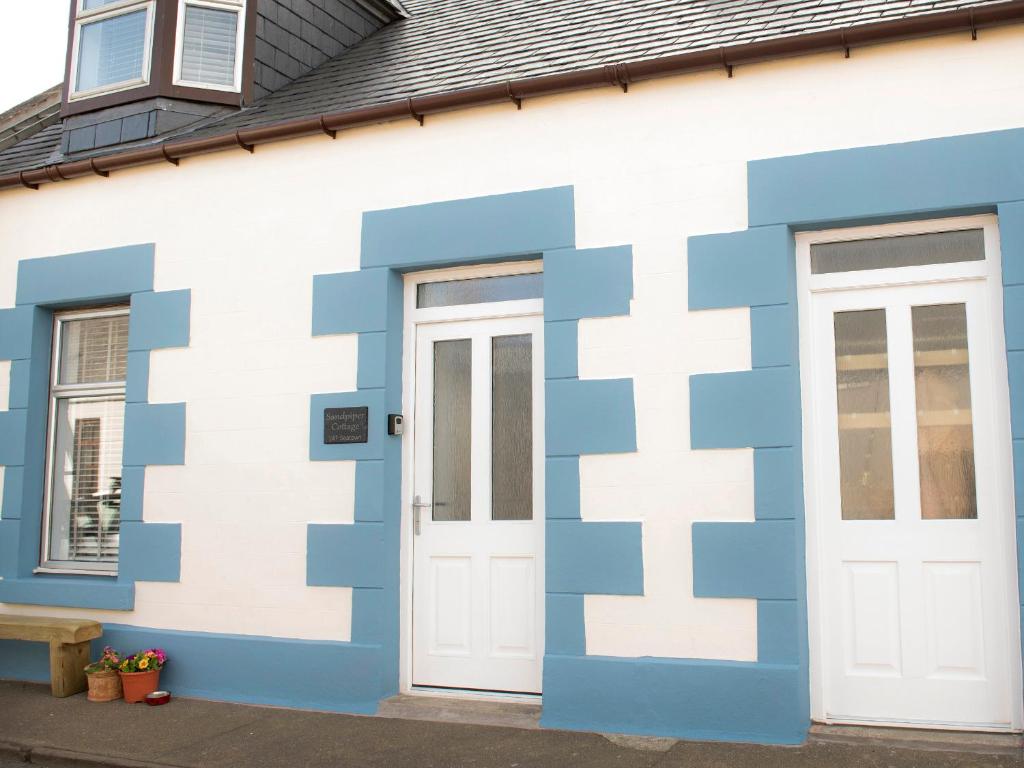 a blue and white building with two doors at Sandpiper Cottage in Buckie