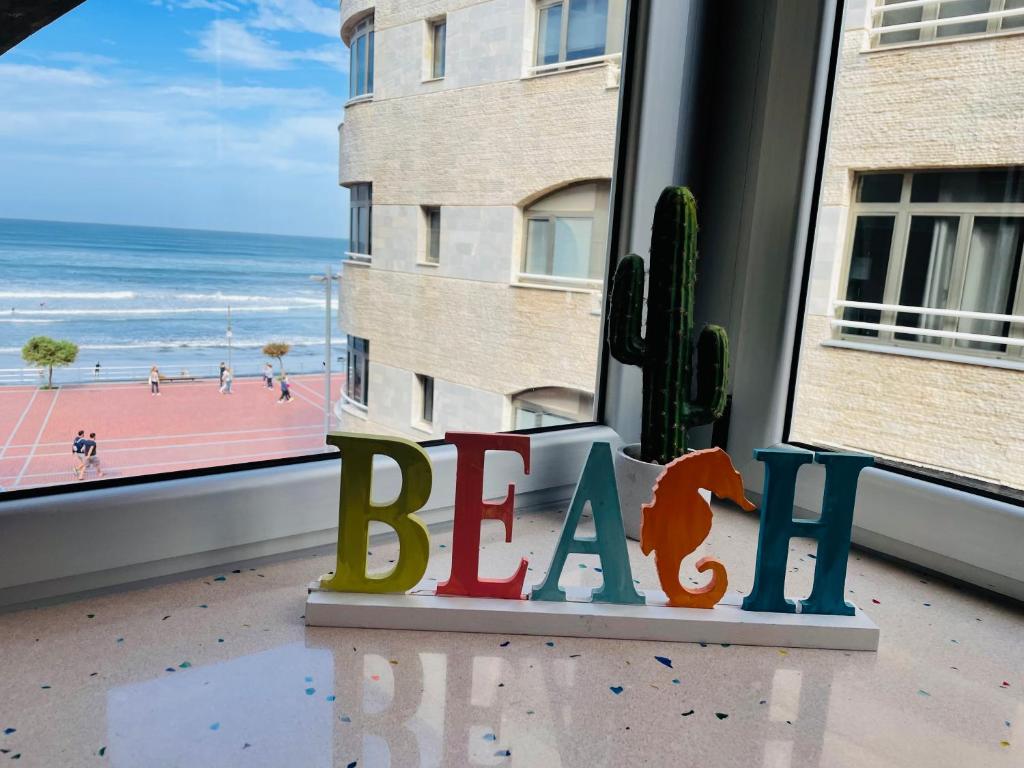 una ventana con vistas a la playa y un cactus en LAS CANTERAS Sabor a Mar 2 Dormitorios "Parking Gratis", en Las Palmas de Gran Canaria