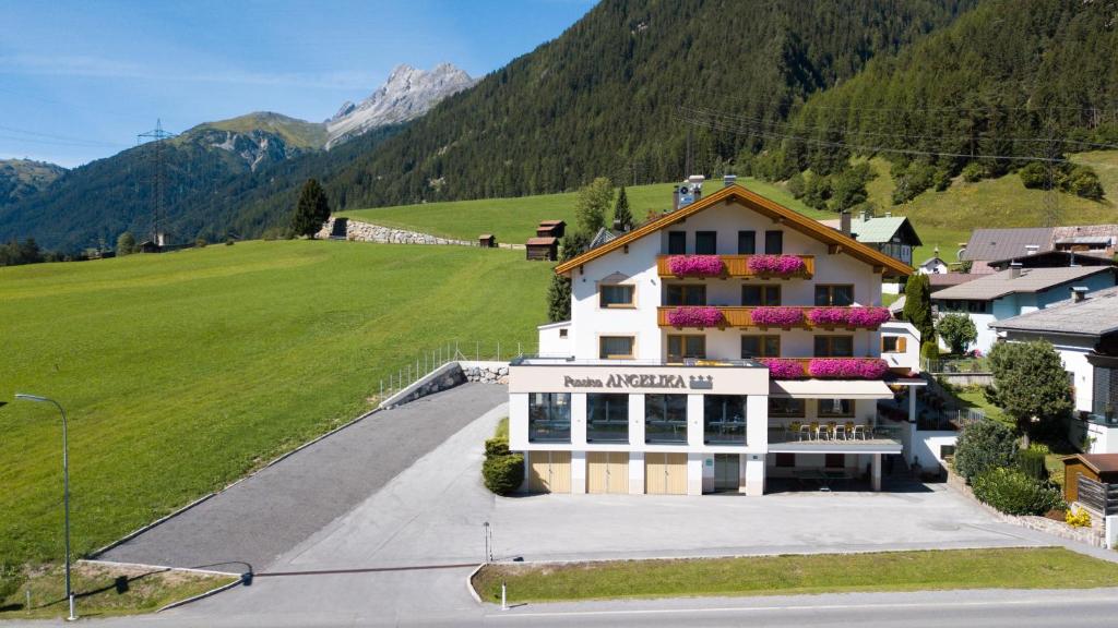duży budynek z kwiatami na poboczu drogi w obiekcie Pension Angelika w mieście Pettneu am Arlberg