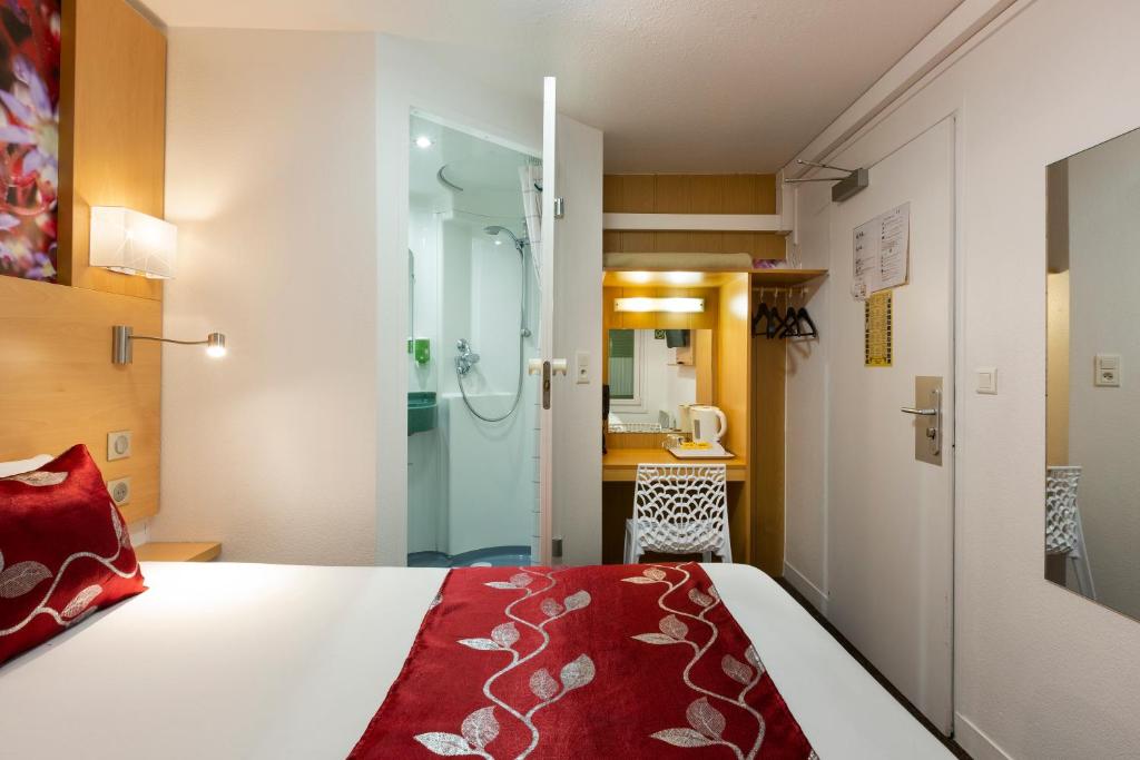 a hotel room with a bed and a shower at Fasthotel Orleans Zénith in Orléans