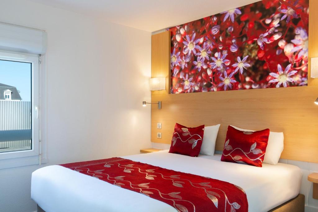 a bedroom with a large bed with a painting on the wall at Fasthotel Orleans Zénith in Orléans