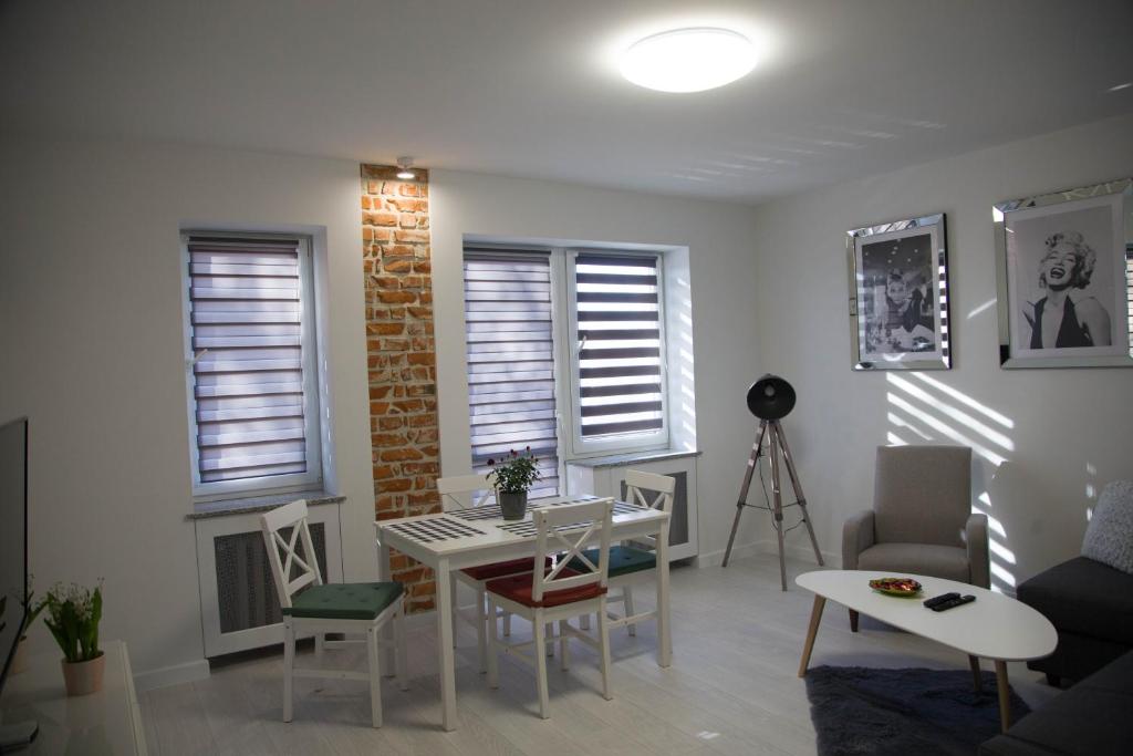 a living room with a table and chairs and windows at Apartament Wrocław Borowska in Wrocław