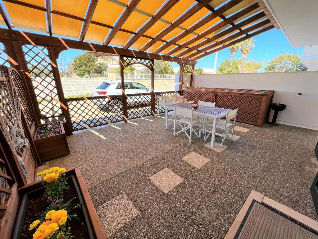un patio con tavolo, sedie e auto di Appartamenti Venerina climatizzati a 50 m dal mare a Torre San Giovanni Ugento