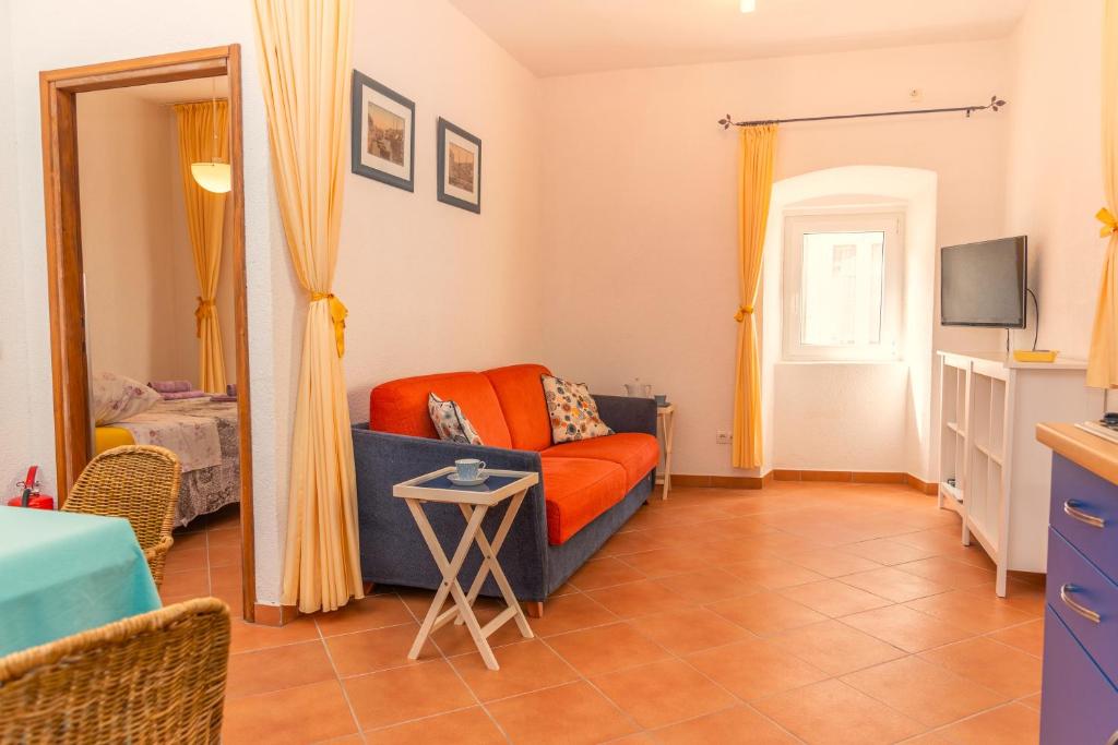 a living room with an orange couch and a television at Sidar-Old Town in Cres