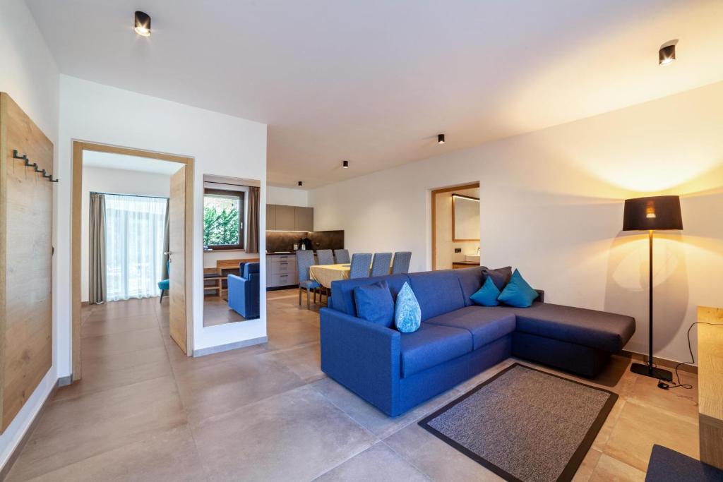 ein Wohnzimmer mit einem blauen Sofa und einer Küche in der Unterkunft Camping Passeier Garten in Saltaus