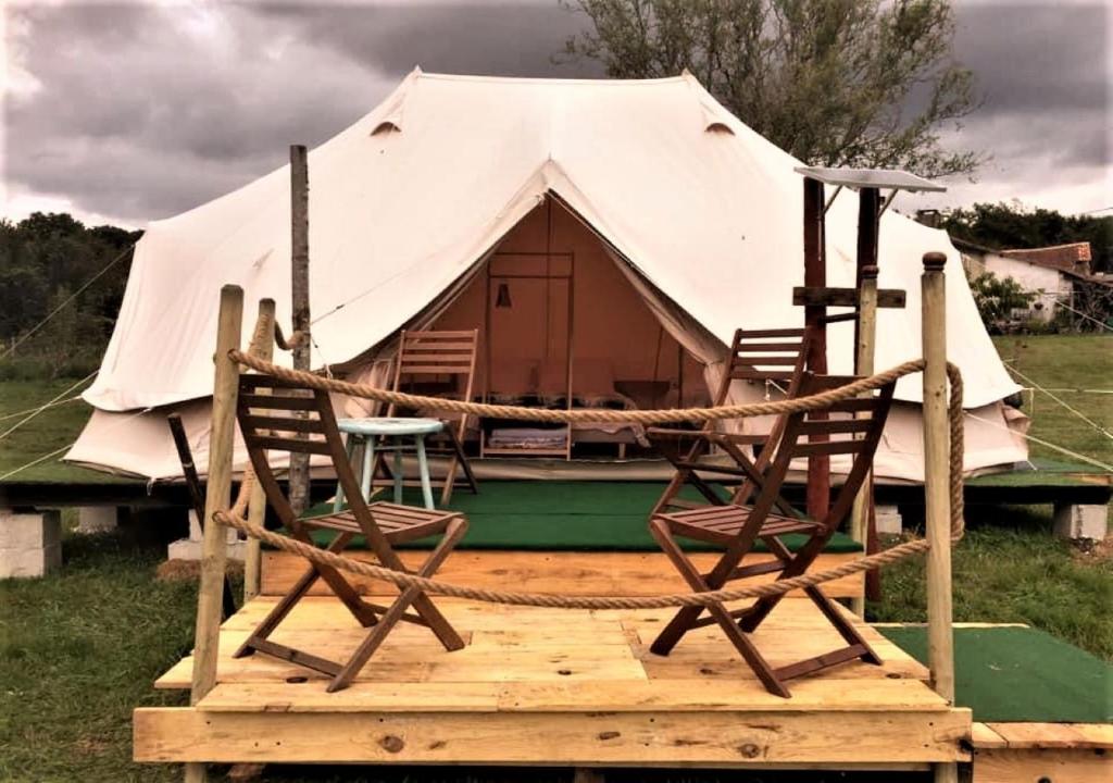 two chairs on a wooden platform in front of a yurt at French Fields Luxury Glamping Twin Emperor Tent in Le-Vieux-Cérier