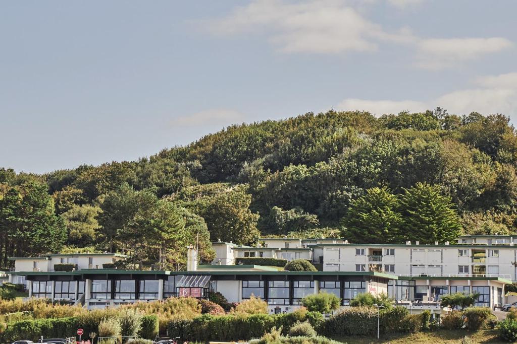 un groupe de bâtiments devant une montagne dans l'établissement Belambra Clubs Colleville-sur-Mer - Omaha Beach, à Colleville-sur-Mer