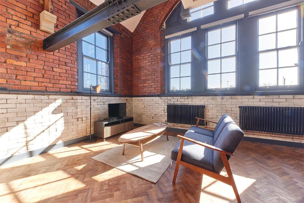 a living room with a brick wall and a chair at No 7 at Simpson Street Apartments Sunderland in Sunderland