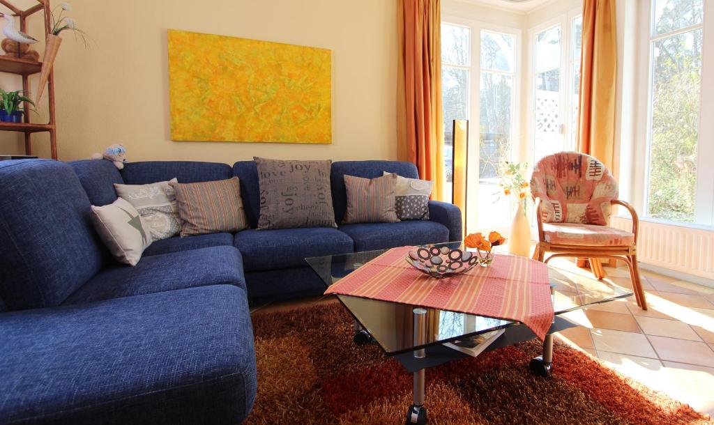 ein Wohnzimmer mit einem blauen Sofa und einem Tisch in der Unterkunft Ferienwohnung Waldblick Nr. 11 in Kühlungsborn