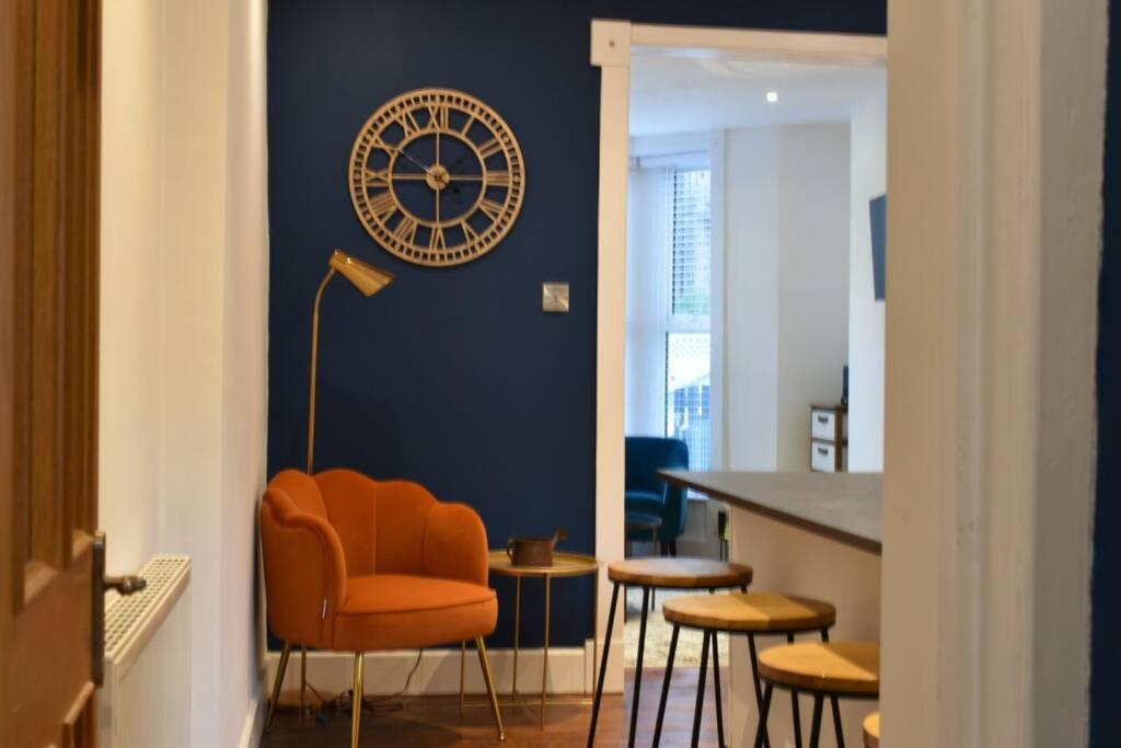an orange chair in a room with a clock on the wall at The Cheltenham, stylish 1-bed Victorian apartment in Harrogate