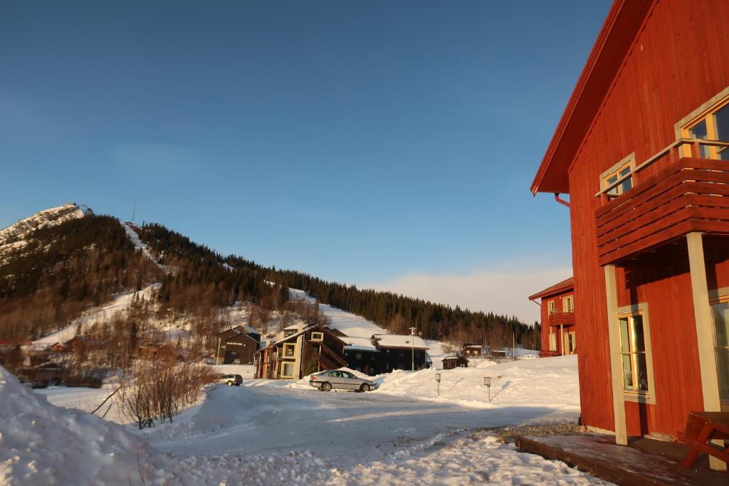 a building with snow on the ground next to a mountain at Funäsdalsporten Röda Husen Funäsdalen in Funäsdalen