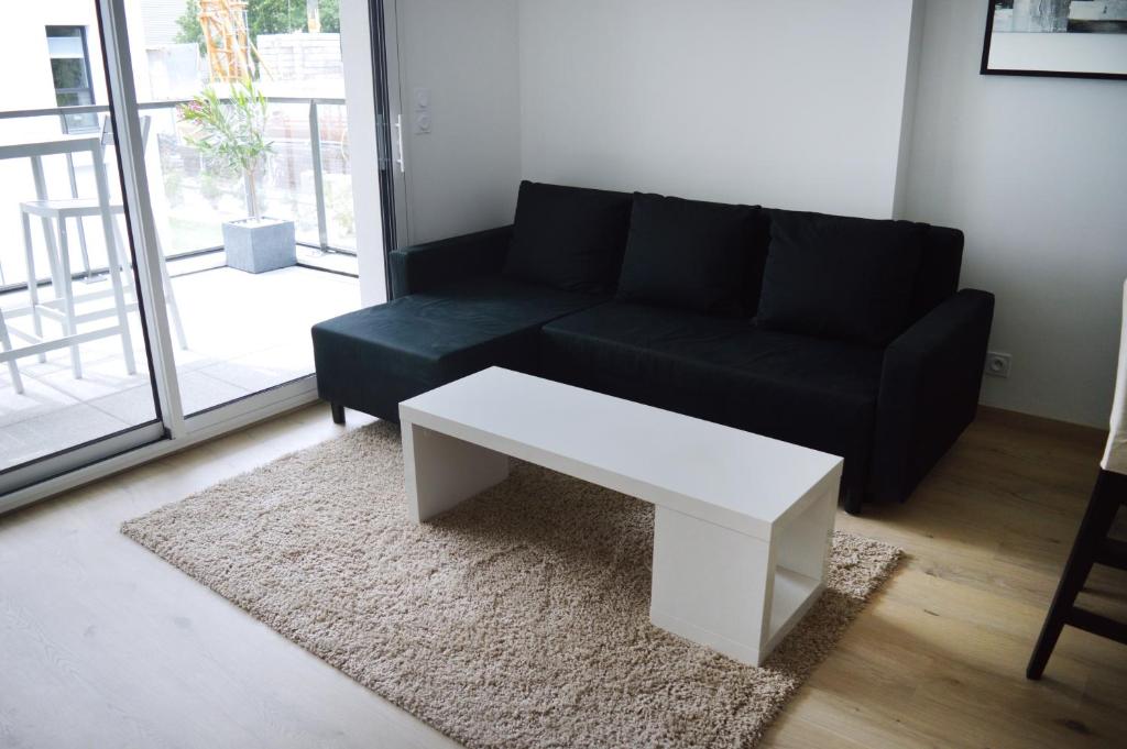 a living room with a black couch and a white coffee table at APPARTEMENT ARRADON / PROCHE MER / TOUT ÉQUIPÉ in Arradon