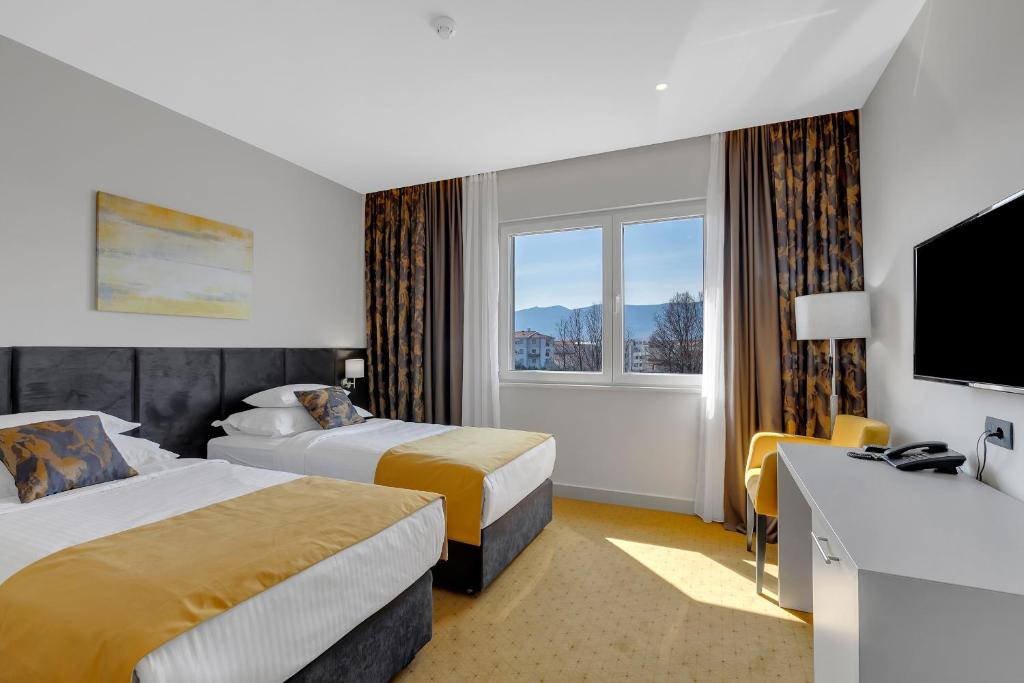 メジュゴリエにあるHotel Marconiのベッド2台とテレビが備わるホテルルームです。