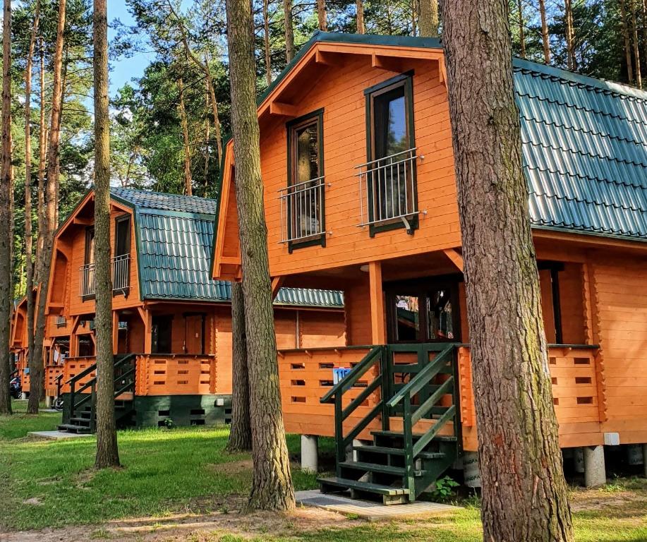 a large wooden cabin in the woods with trees at Ośrodek Wypoczynkowy Kormoran Niesulice in Niesulice