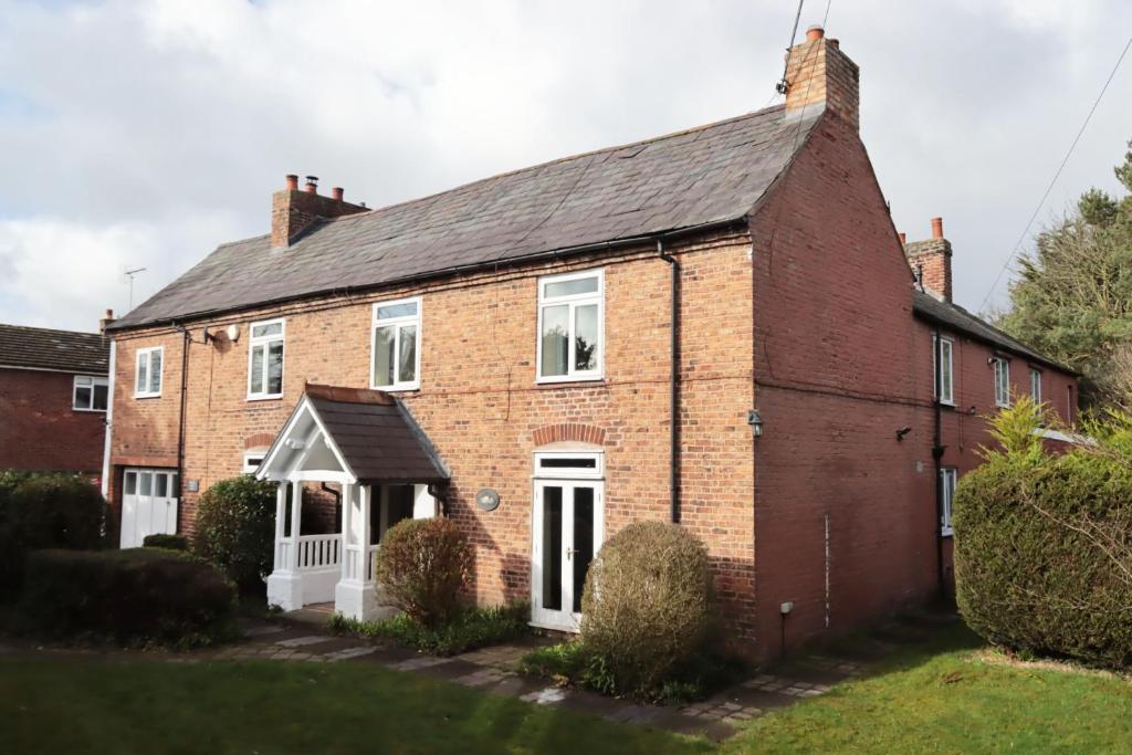 an old red brick house with a white door at Bretton House Farm Retreat in Chester