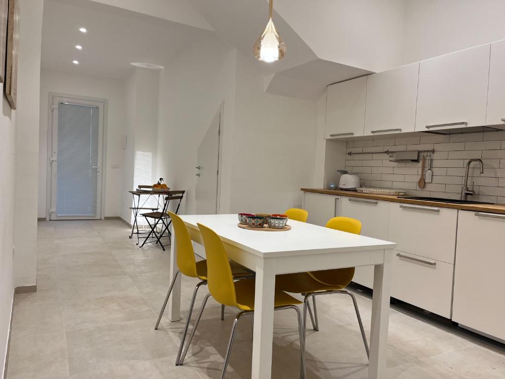 una cucina con tavolo bianco e sedie gialle di Casa Vacanze Portopalo.66 a Portopalo