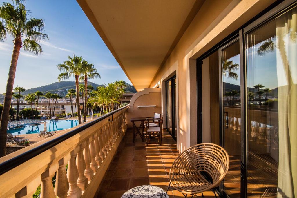 een balkon met uitzicht op het zwembad en de palmbomen bij Mon Port Hotel & Spa in Port d’Andratx