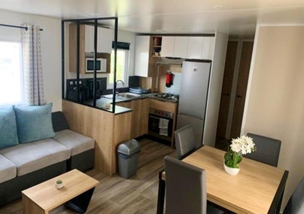 un petit salon avec un canapé et une cuisine dans l'établissement Bungalow confortable à Saint-Jean-de-Monts avec piscine partagée, à Saint-Jean-de-Monts