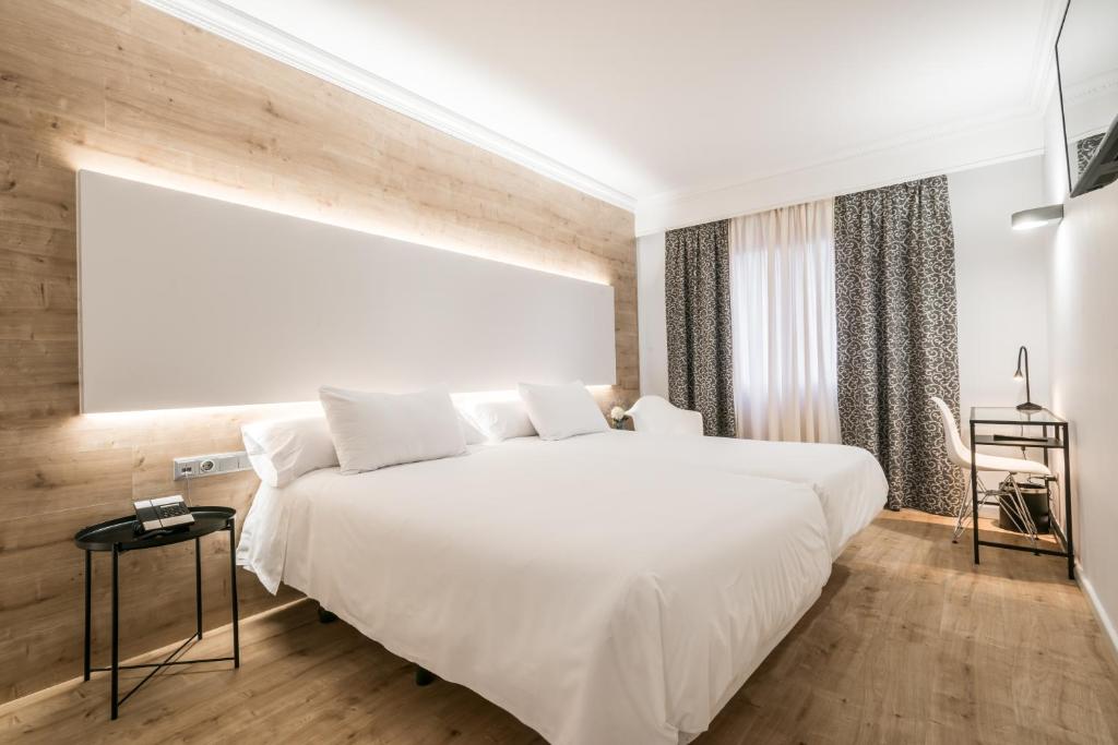 a bedroom with a large white bed and wooden floors at Hotel Sansi Park in Lleida