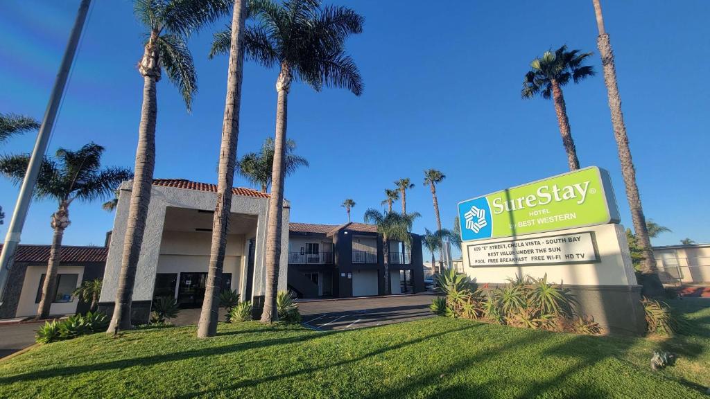 a sign in front of a building with palm trees at SureStay Hotel by Best Western Chula Vista San Diego Bay in Chula Vista