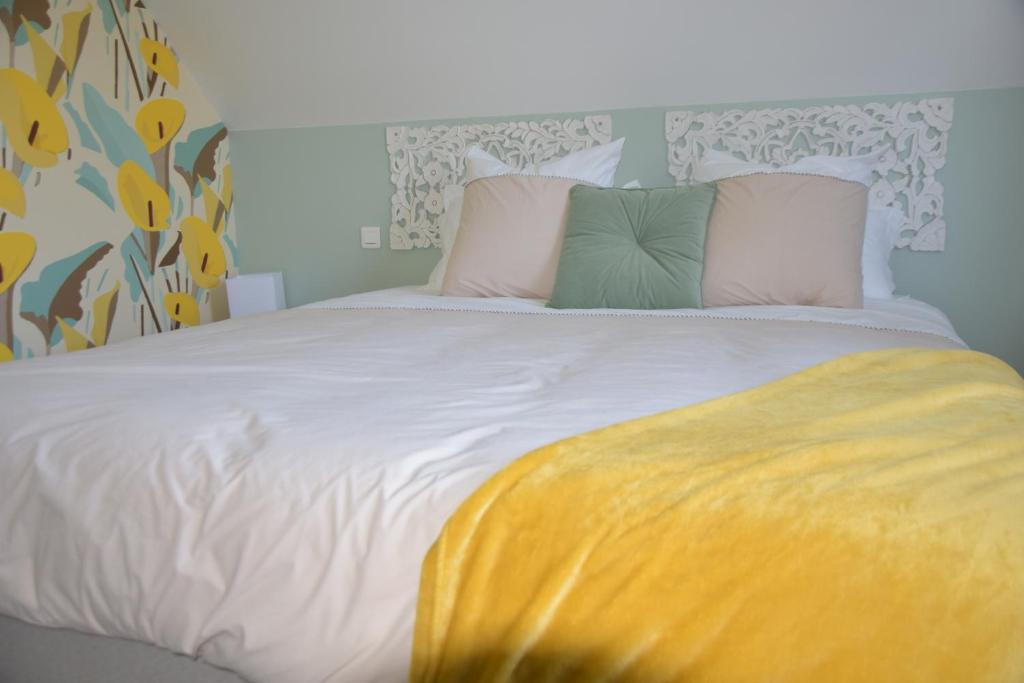 a white bed with two pillows and a yellow blanket at Les chambres du Vert Galant "Coucher de soleil" in Verlinghem