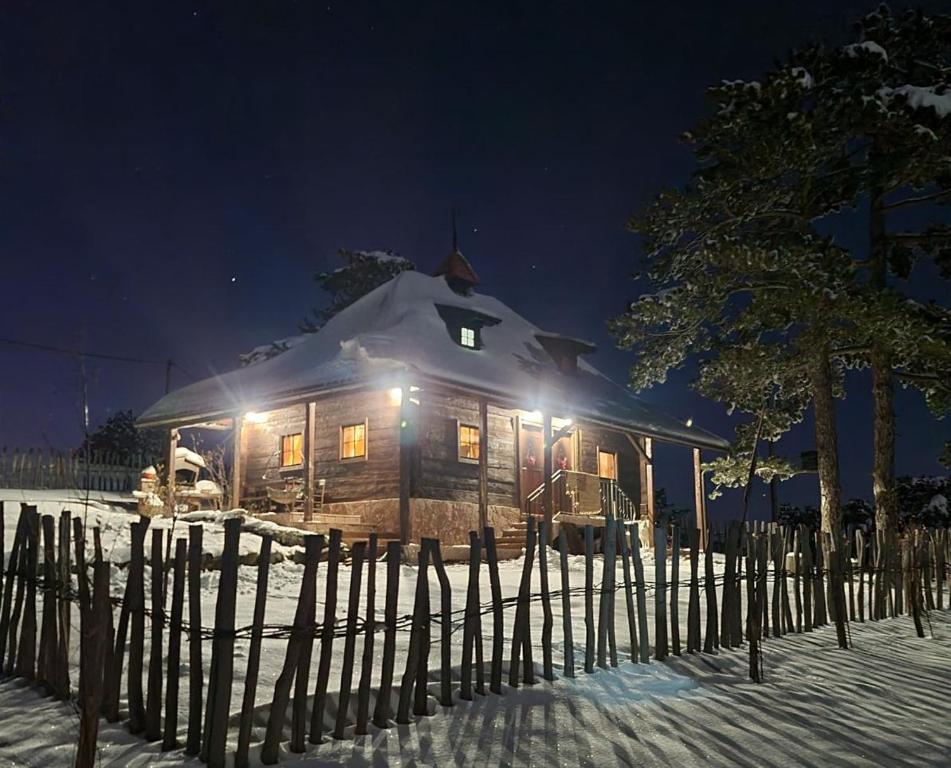 a log cabin with snow on the roof at night at Zlatiborski katuni in Zlatibor