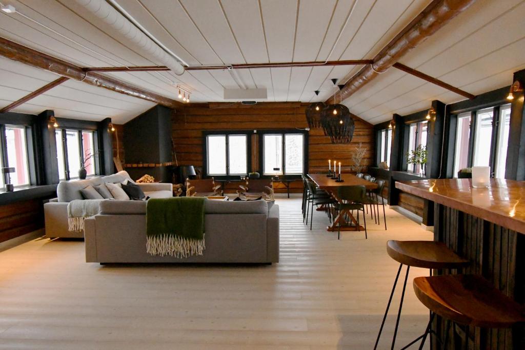 a living room with a couch and tables and windows at Skars Lodge / North Mountain Lodge in Funäsdalen