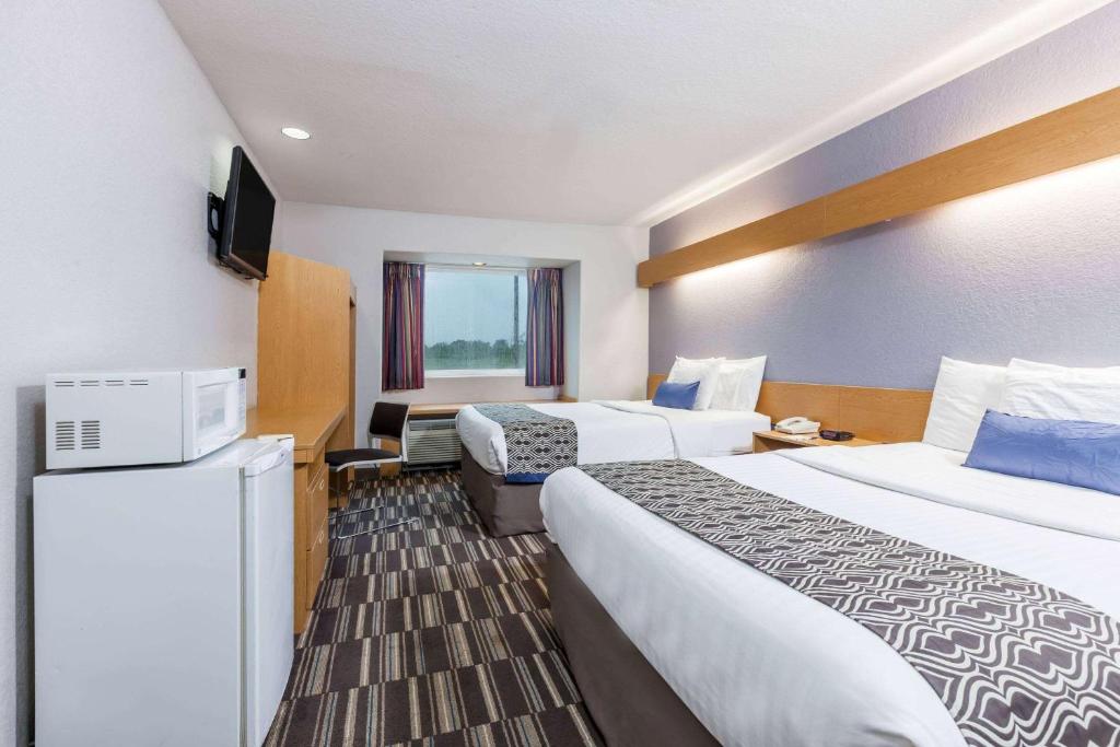 a hotel room with two beds and a television at Microtel Inn & Suites by Wyndham Ardmore in Ardmore