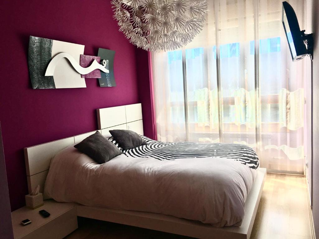 Dormitorio con paredes moradas, cama y lámpara de araña. en Burgos Rachel Swim & Paddle, en Burgos