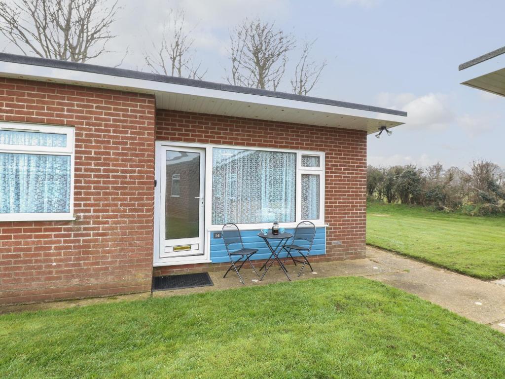 a brick house with a table and chairs in the yard at 14 Siesta Mar in Norwich