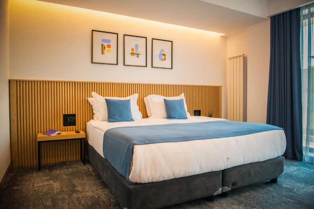 um quarto de hotel com uma cama grande com almofadas azuis em Hotel Vigo, Eforie Nord em Eforie Nord