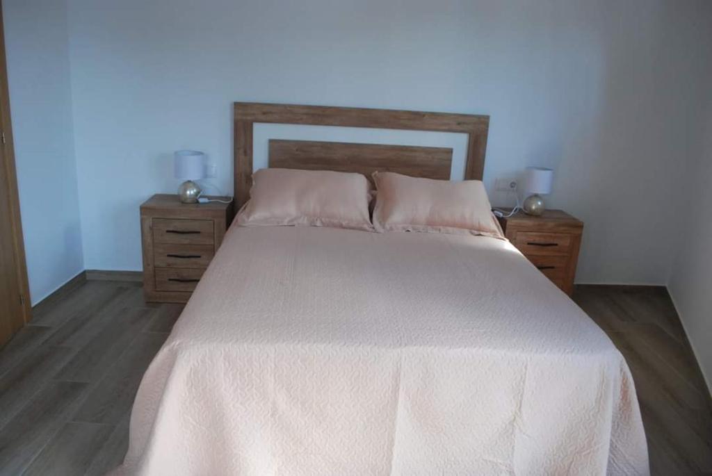 a bed with a white bedspread and two night stands at Casa Rural Carmen Atzeneta in Adzaneta