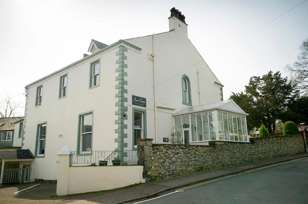 a white building with a stone wall next to a street at Acorn House in Keswick