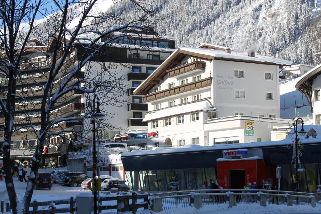 a building in the snow next to a snow covered mountain at Hotel Garni Golfais in Ischgl