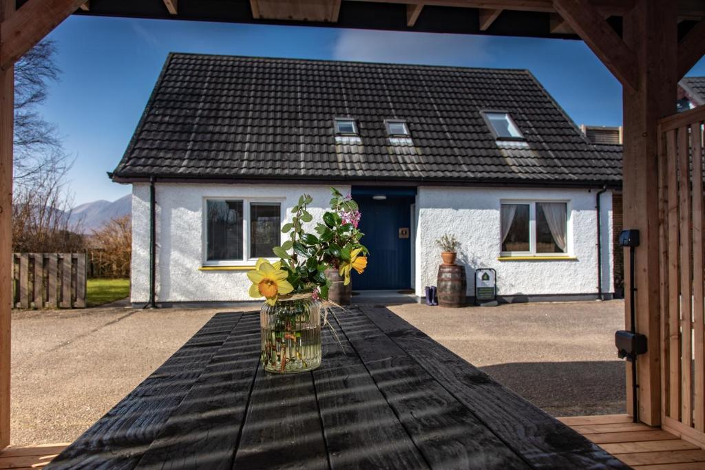 a vase of flowers on a table in front of a house at Croft4 in Broadford