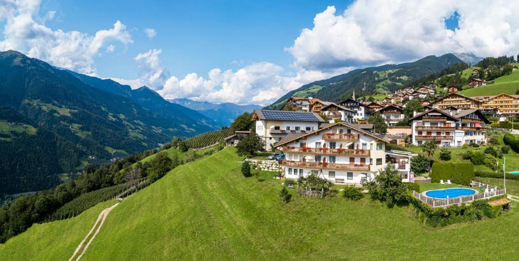 a resort on a hill with mountains in the background at Gasserhof Garni & Apartment in Schenna