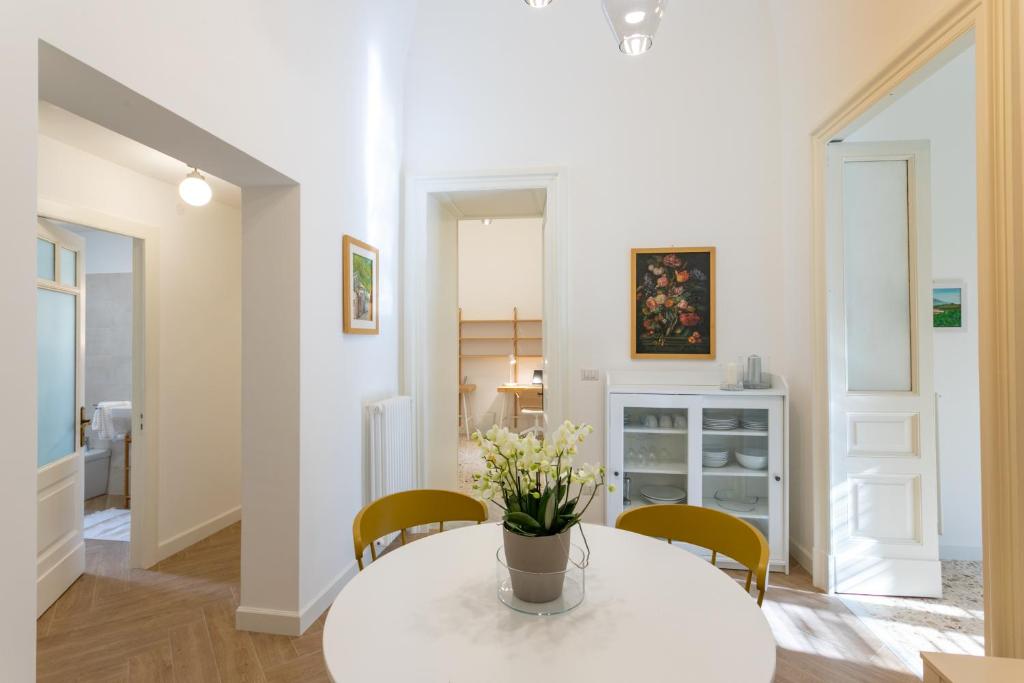 einen weißen Tisch mit Stühlen und eine Vase mit Blumen darauf in der Unterkunft VITTORIO EMANUELE HOUSE in Catania