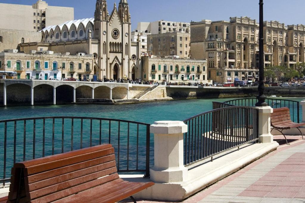 a couple of benches sitting next to a body of water at Modern 2 Bedroom Maisonette in Central Sliema in Sliema
