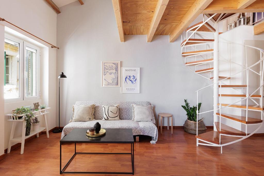 a living room with a couch and a spiral staircase at Calypso Apartment by Konnect, Corfu Old Town in Corfu