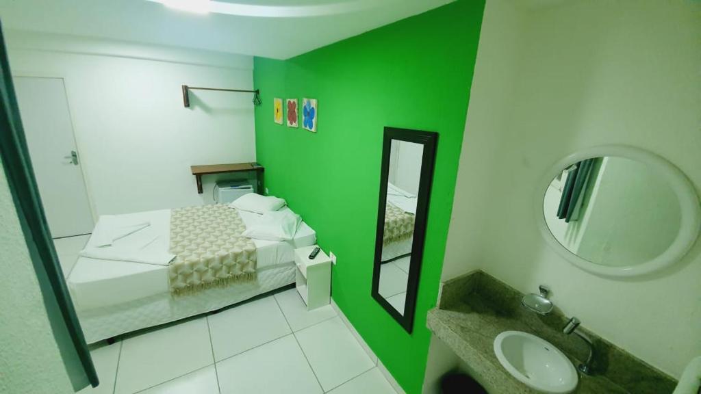 a green room with a bed and a mirror at Pousada Pedras do Porto in Porto De Galinhas